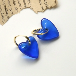 Détail de breloques cœur en résine bleu Klein sur créoles dorées et papier vintage