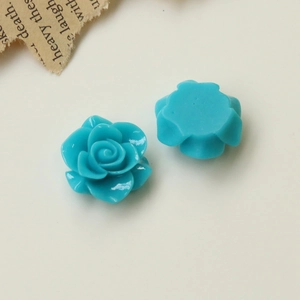 Detailed macro view of cyan blue resin camellia charms showing front relief and flat back