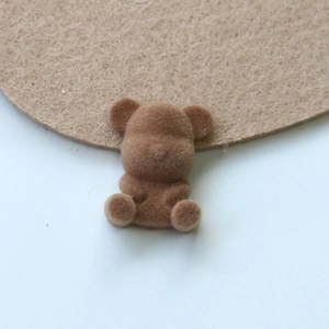 Macro detail of a brown flocked teddy bear patch for DIY jewelry and accessories