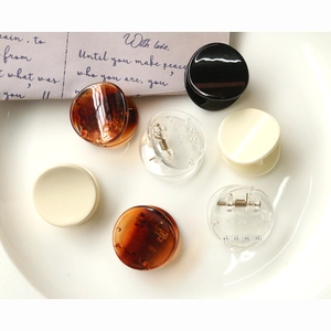 Minimalist geometric round resin hair claws in assorted colors on a white ceramic plate
