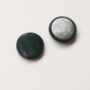 Macro view of dark green faux leather magnetic buttons with textured surface and metal back