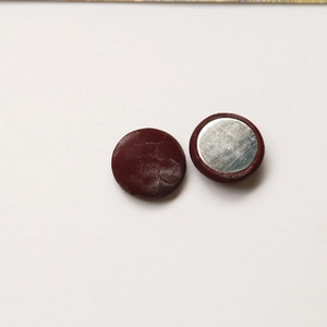 Macro detail of round dark brown snake pattern leather buttons with silver metal backing