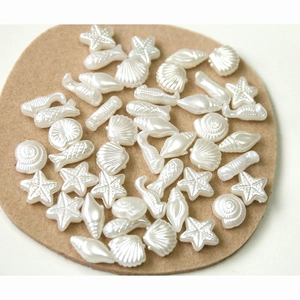 Macro view of pearlescent sea shells and starfish resin beads for DIY jewelry making