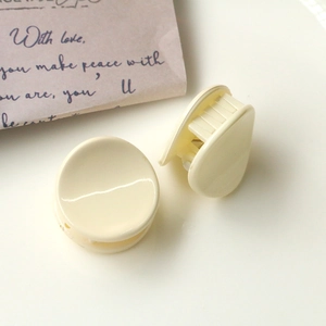 Detail of cream resin mini hair clips in round and teardrop shapes on white background
