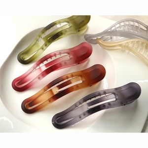 Matte resin hair clips in six colors including olive green and amber brown on a white tray