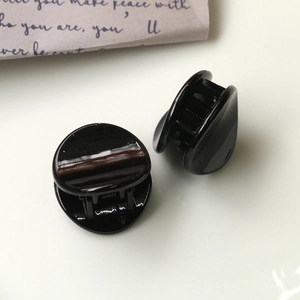Close-up of two small black resin hair clips with glossy finish and interlocking teeth