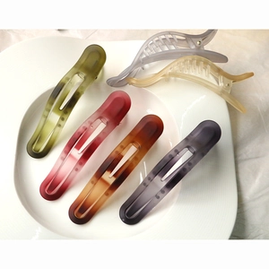 Detail of matte resin hair clips in assorted colors displayed on a white ceramic plate