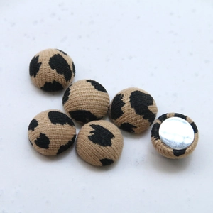 Macro shot of fabric-covered leopard print buttons with flat silver metal backs