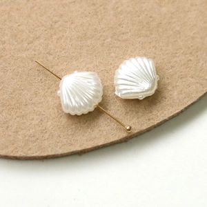 Macro detail of pearl white shell charm with golden pin for DIY jewelry making crafts