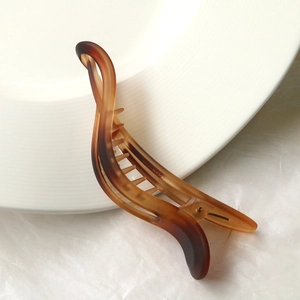 Detail of amber resin banana clip with twist design and gradient brown finish
