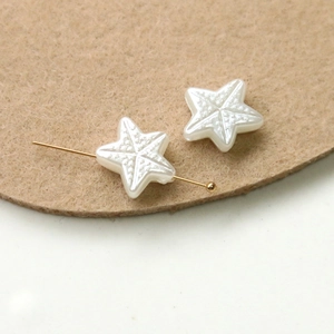 Detailed view of a white pearlescent starfish bead with a gold pin through its center