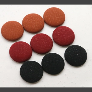 Detailed view of nine fabric covered buttons with cross-grid texture in earthy tones