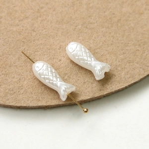 Detailed view of small white fish-shaped pearl beads with intricate scale textures