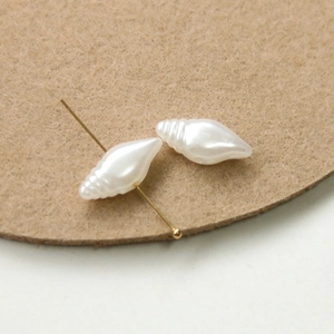 Close-up of shell-shaped cream white faux pearls with a gold pin for DIY jewelry making