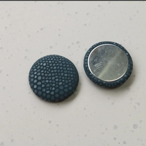 Detailed close-up of blue pebbled leather texture buttons with silver metal backing