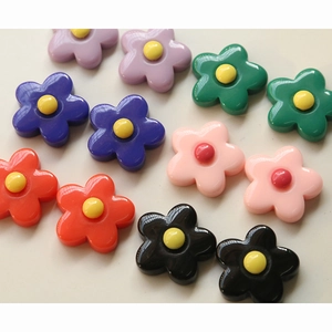 Flat lay of colorful five-petal resin flower charms for DIY jewelry and phone case crafts