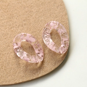 Macro shot of semi-transparent pink ink-splatter acrylic earring components for DIY crafts