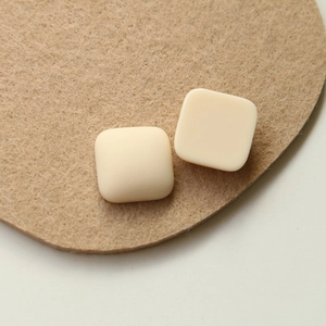 Dettaglio di patch quadrati in resina crema opaca per gioielli fai-da-te su feltro