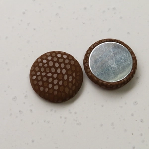 Detailed view of round snakeskin texture buttons with flat silver metal back for DIY crafts
