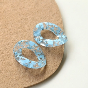 Macro shot of blue splattered ink pattern on transparent acrylic twisted chain link accessories