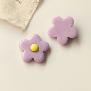 Macro detail of purple resin five-petal flower charms with yellow center for DIY crafts