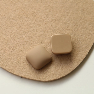 Dettaglio di componenti quadrati in resina per gioielli fai-da-te con finitura caramello opaca