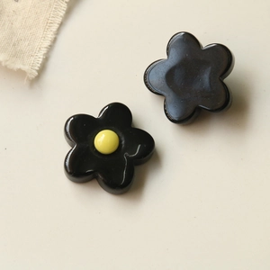 Detail of DIY black resin five-petal flower charms with yellow center for crafts