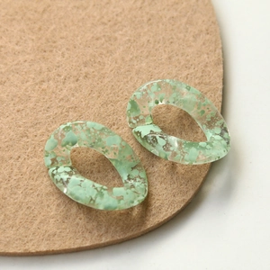 Macro shot of light green translucent acrylic oval link with ink splash effect detail