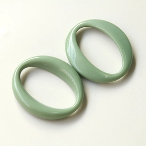 Close-up of light green oval acrylic geometric pendants for DIY jewelry and accessories