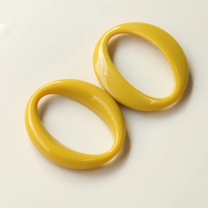 Close-up of bright yellow oval acrylic jewelry components with a polished glossy finish