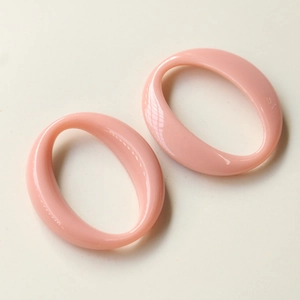 Close-up of pink oval acrylic pendant accessories with smooth polished resin finish