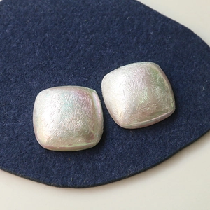 Breloques carrées en résine irisées avec fini perlé et texture brossée sur fond bleu