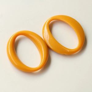 Detail view of two orange hollow oval acrylic pendants for DIY jewelry making