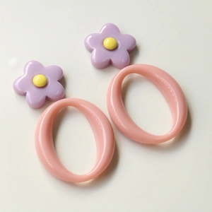 Detailed view of acrylic geometric oval pendant with purple flower and pink resin loop