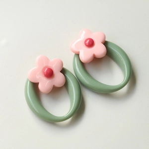 Detailed view of colorful flower resin charms with green oval loops for DIY crafts