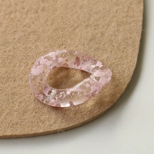 Macro detail of acrylic chain links with pink ink-wash patterns on felt base