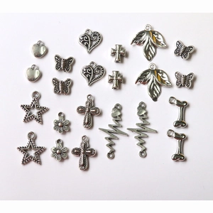 Flat lay of vintage silver alloy charms in various shapes like hearts, butterflies and crosses