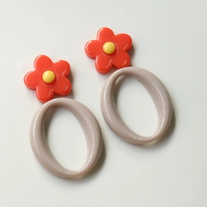 Detail of red floral charms and oval acrylic hoops for DIY jewelry making and earring design