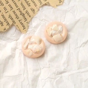 Détail d'un bouton rond en résine pêche avec incrustations de coquillages pour DIY