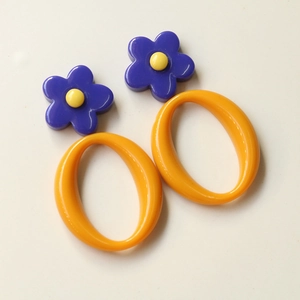 Detail of colorful acrylic flower earrings with purple petals and orange oval rings