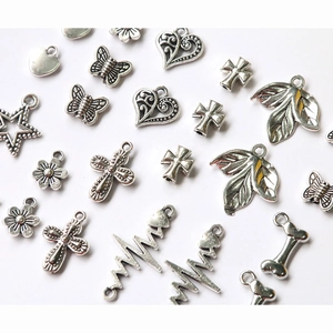Macro shot of assorted vintage silver alloy charms featuring hearts, butterflies, and crosses
