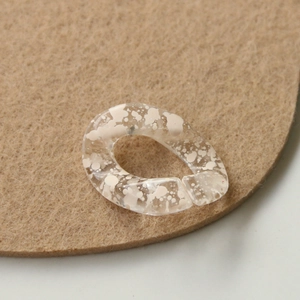 Macro shot of ink-splattered acrylic chain links on textured brown felt background