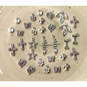 Macro detail of assorted vintage silver alloy charms featuring cross and heart shapes