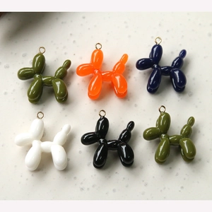Flat lay of colorful resin balloon dog charms in six glossy finishes with gold jump rings