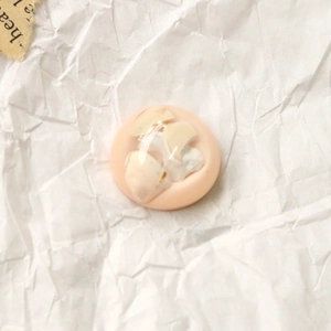 Détail macro d'une breloque ronde en résine avec feuille d'or et nacre pour bijoux DIY