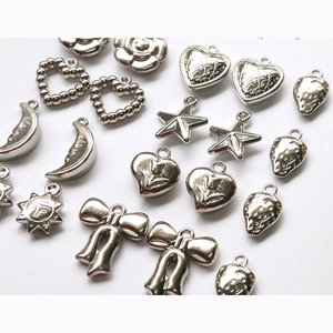 Macro shot of assorted silver alloy DIY charms with rose and star relief details