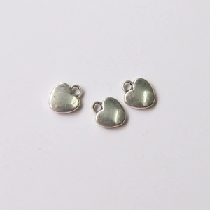 Close-up of three vintage silver alloy heart pendants for DIY jewelry making