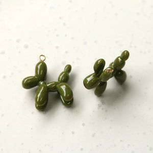 Macro view of olive green balloon dog charms with glossy enamel finish and gold rings