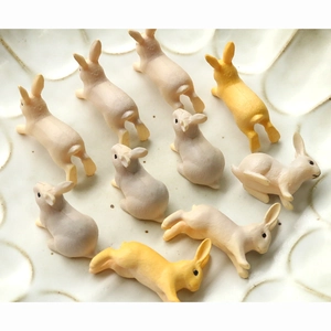 Figurines de lapins miniatures en résine posées sur une assiette en céramique blanche