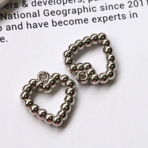 Detailed close-up of two silver heart charms with beaded texture for DIY jewelry making